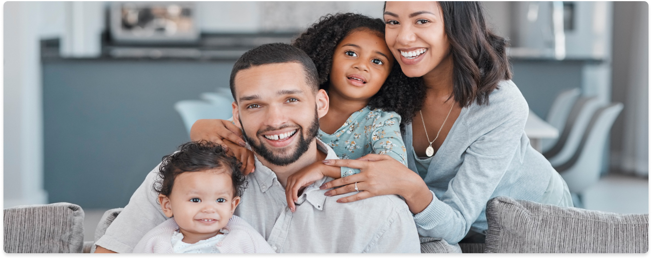 A family is smiling while sitting on a couch.
