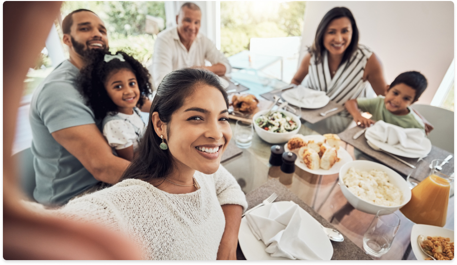 A family is taking a selfie at a dinner table.