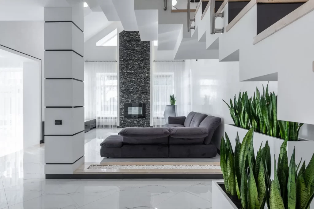A white living room with plants and stairs.