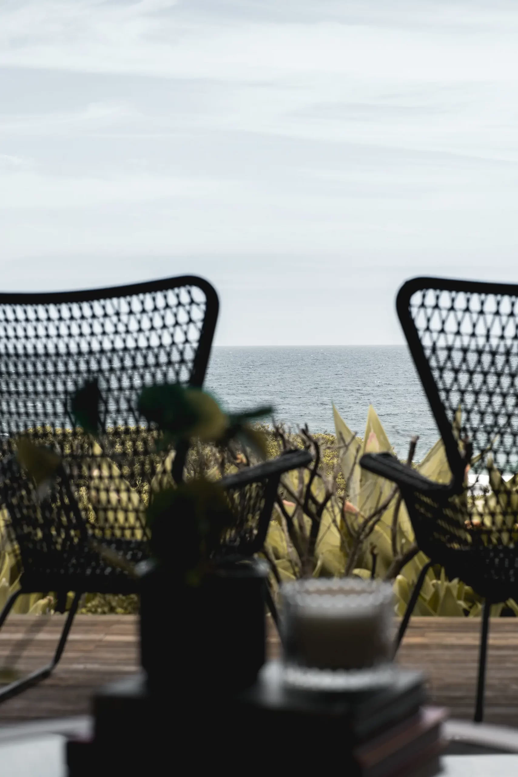 Two chairs on a deck overlooking the ocean.