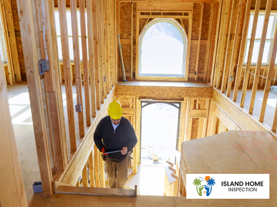 Construction worker reviewing plans inside a partially completed wooden frame of a building.